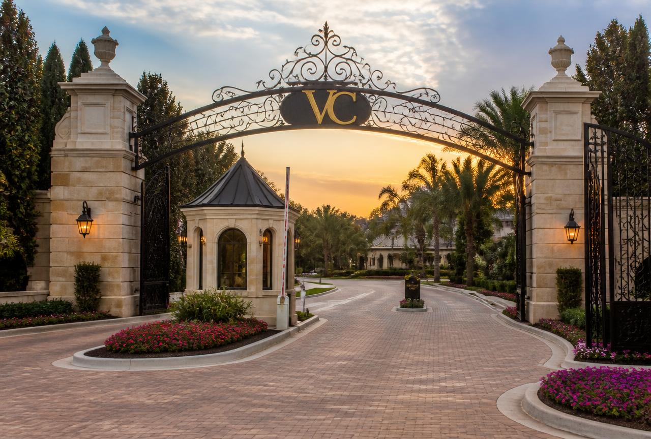 Gated entry to a VC Village Community with VC lettering on the archway and a security booth